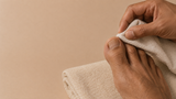 Hand holding a beige towel against a beige background